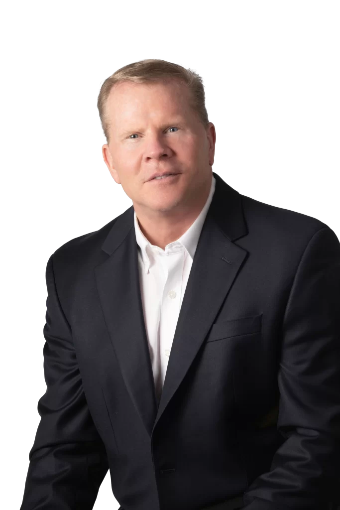 Smiling man in a dark suit and white shirt, seated confidently. CEO of Advanced Digital Automotive Group.