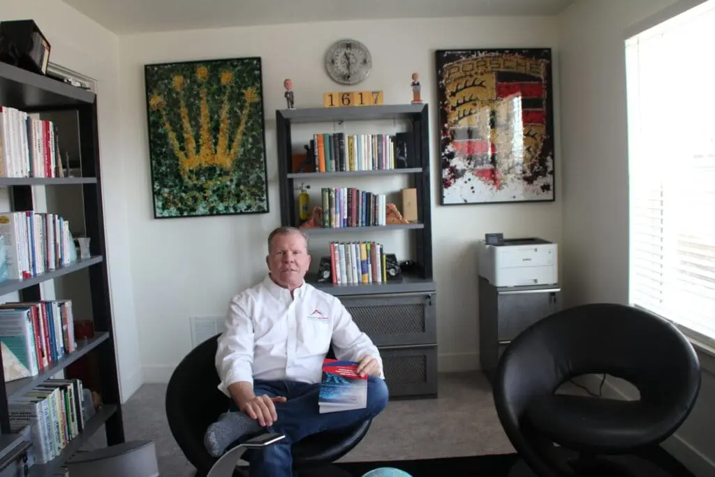 The CEO of Advanced Digital Automotive Group sits in a modern office, holding a magazine, surrounded by books.