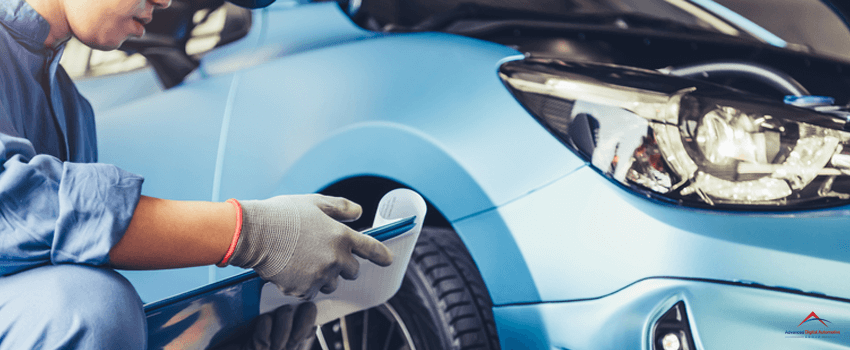 In an auto repair shop, a car mechanic technician checks the maintenance vehicle claimed by the customer with a clipboard.